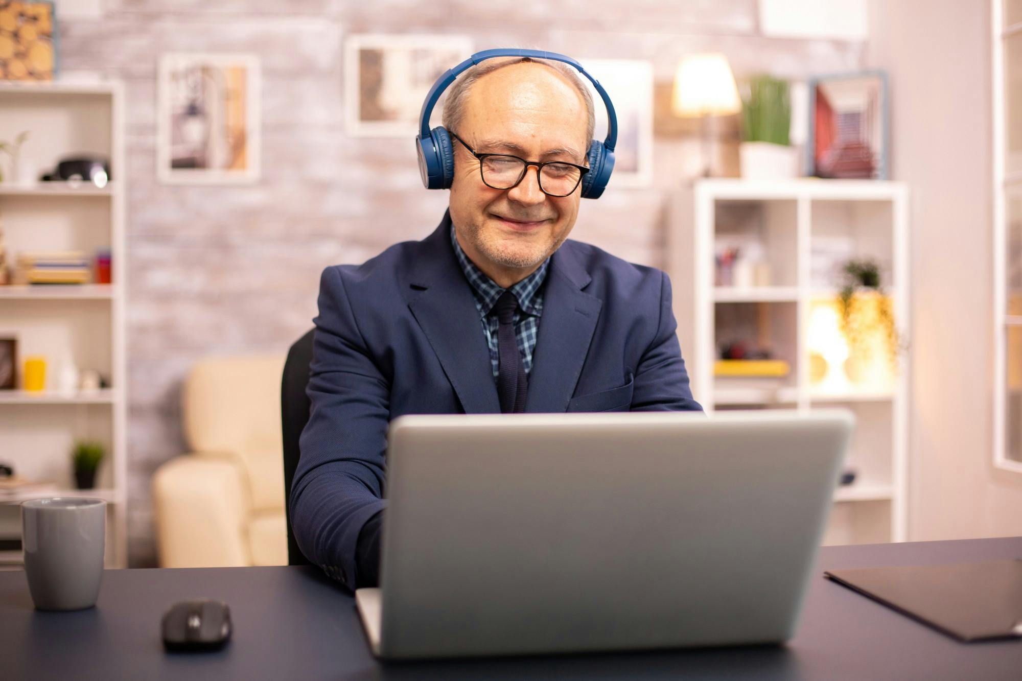 elderly-man-his-60s-with-headphones-his-head-listening-music-working-modern-laptop