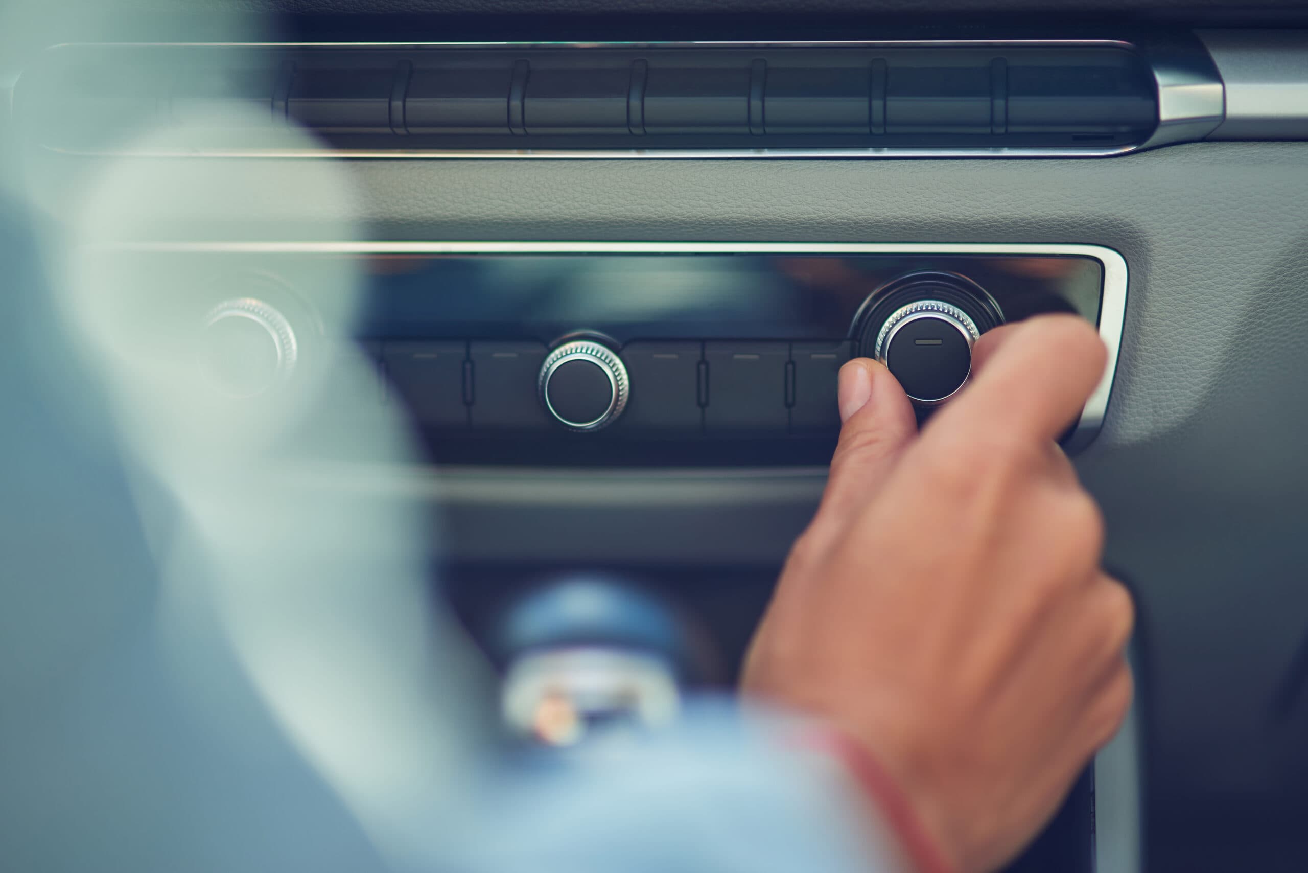 Listening music, cropped shot of a woman turning on radio while driving in the city, close up