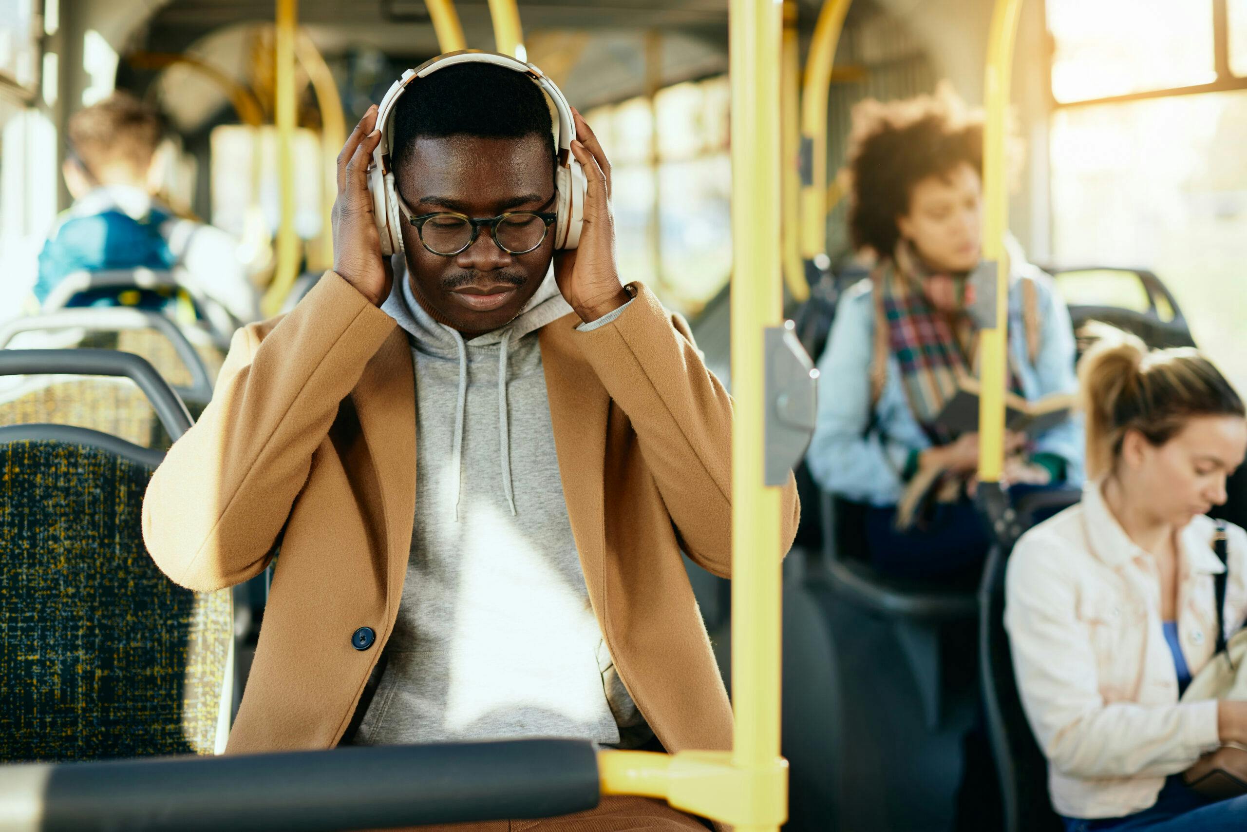 Young black man listening music over headphones while commuting